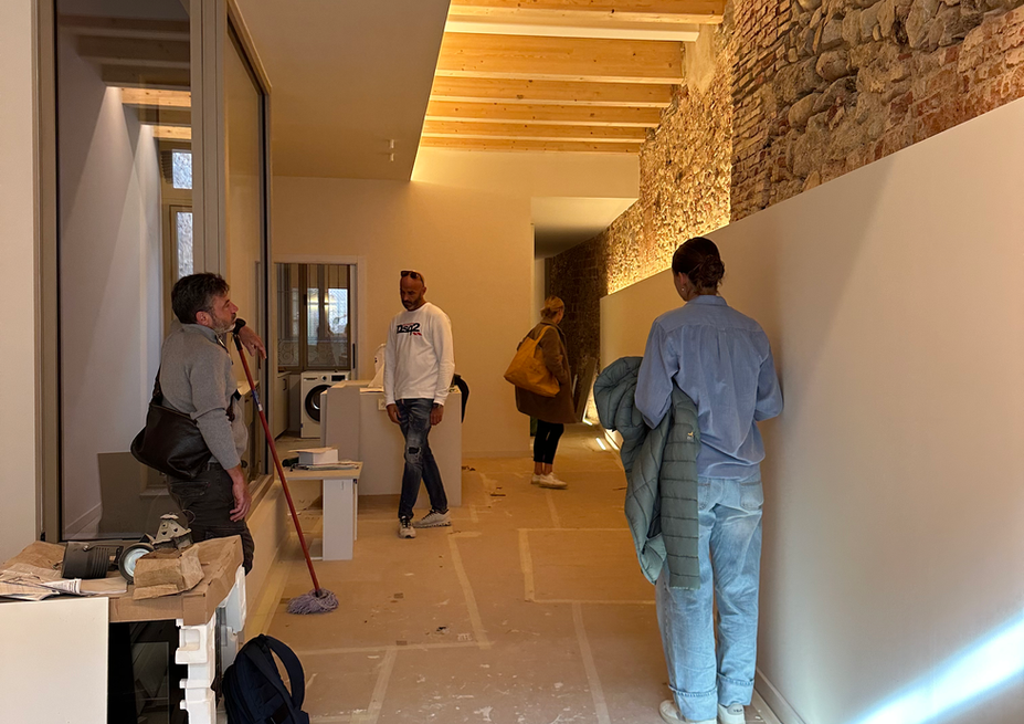 Four people inspecting a renovated hallway with exposed beams and stone wall.