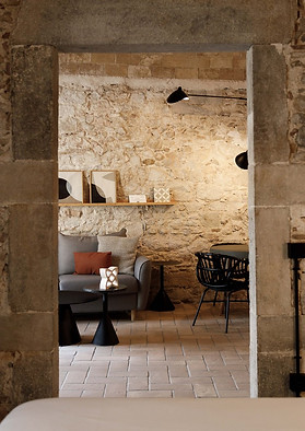 Interior view of La Comuna apartment, looking at a partial view of the sofa against an old stone wall