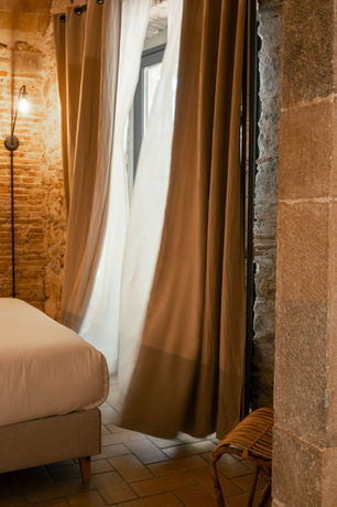 Bedroom at La Comuna with stone walls and long curtains