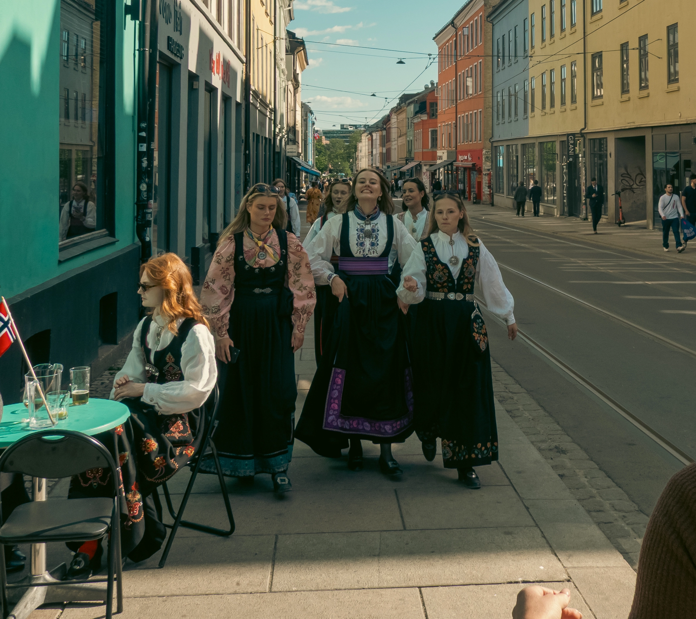 A group of girls walking down the sidewalk in Oslo, Norway wearing tradition Norwegian bunads for Constitution Day.