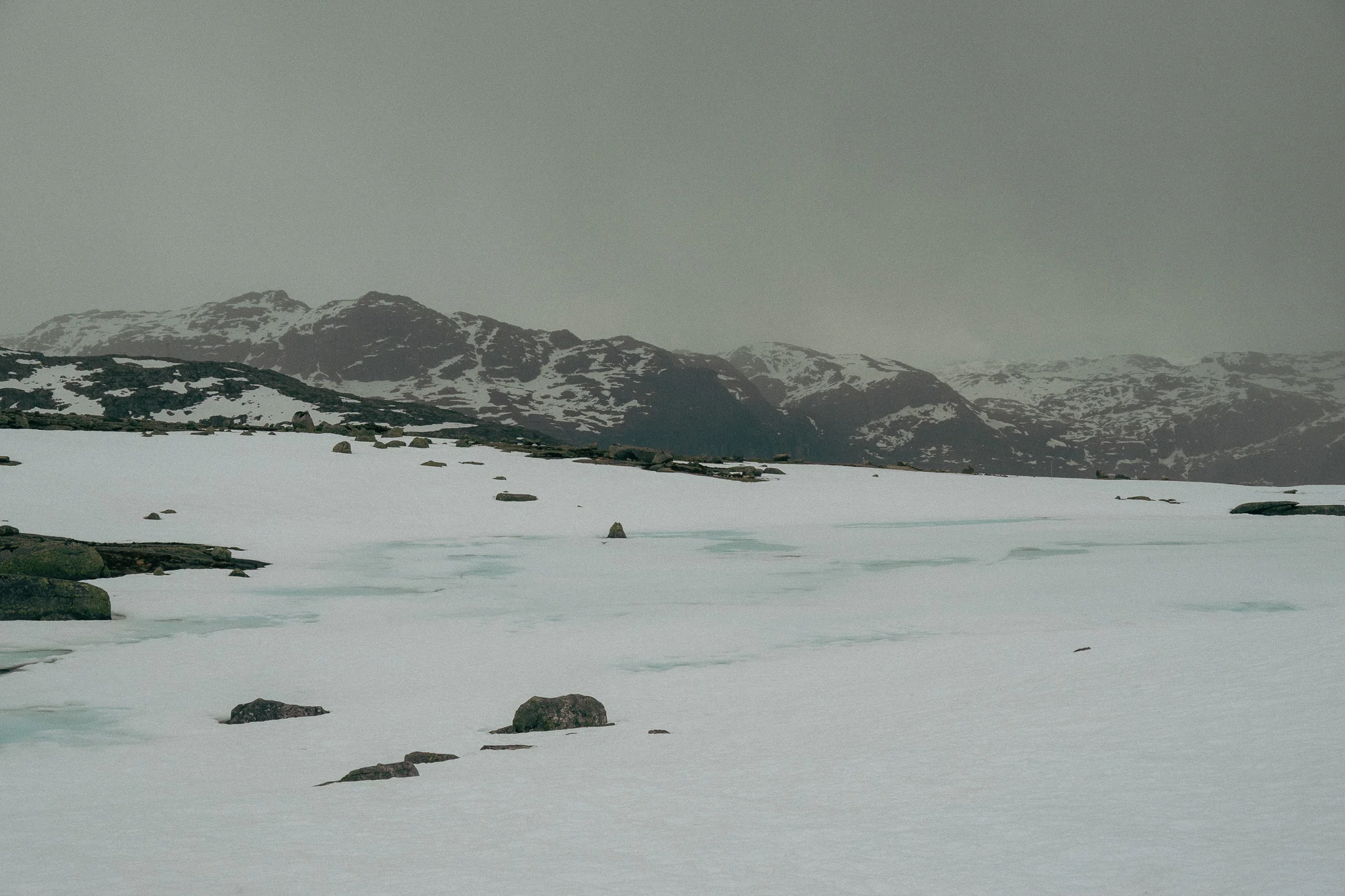 Dark cloudy skies and hailstorm forming with snow and rocks surrounding the Trolltunga trail in Norway