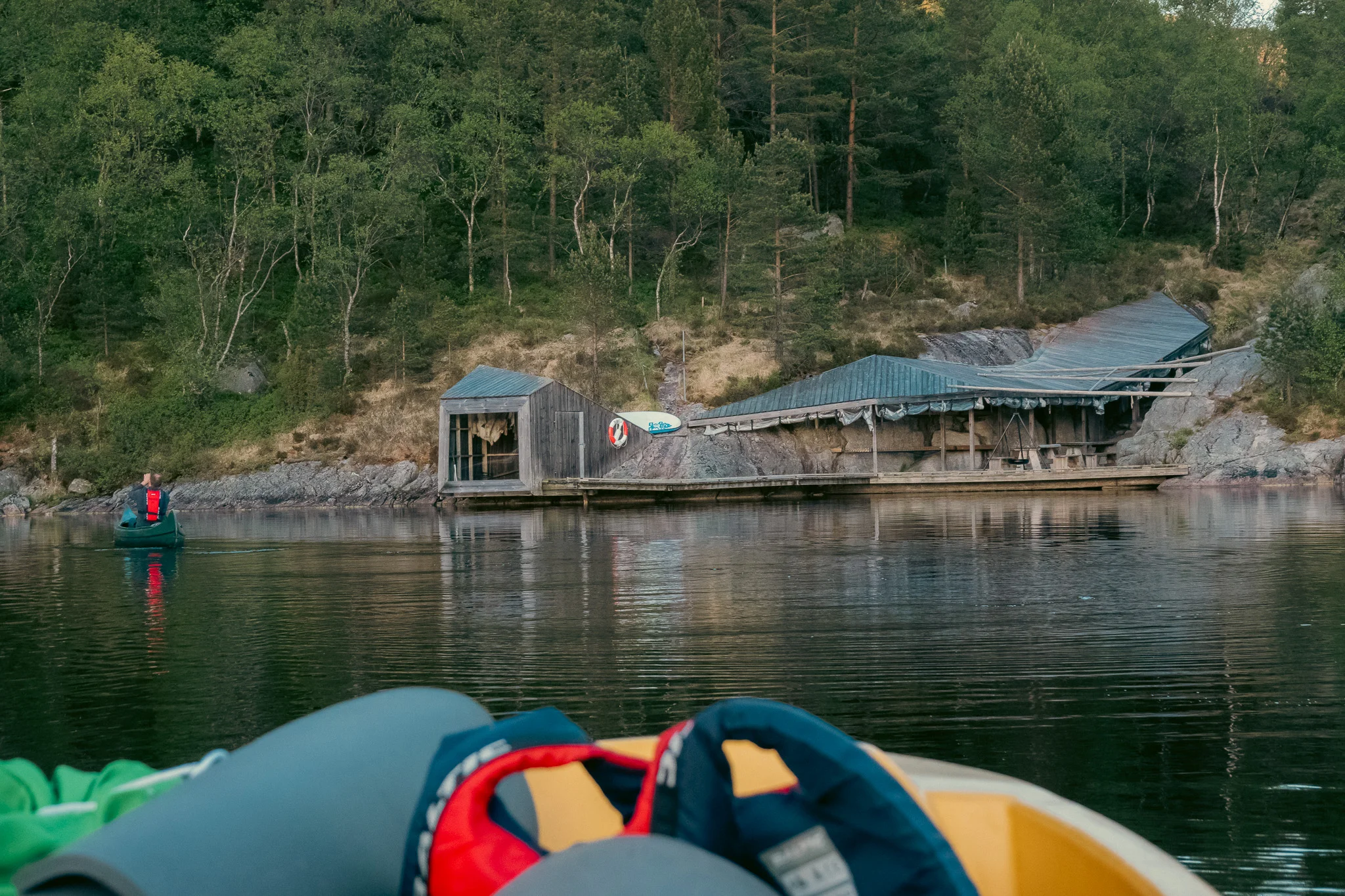 A lake side campsite with a wooden dock and shelter on a lake at sunset.