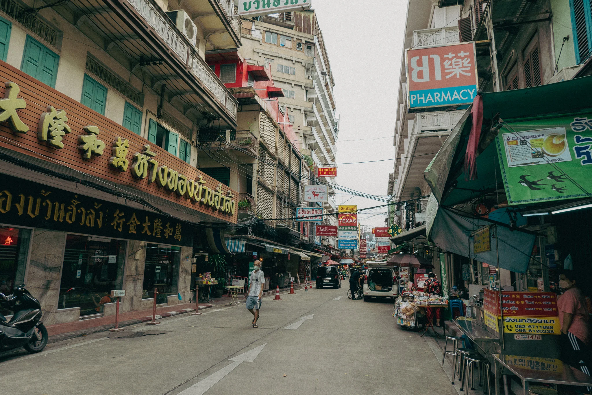 A city street in Bangkok Thailand with people walking and shops lined on either side