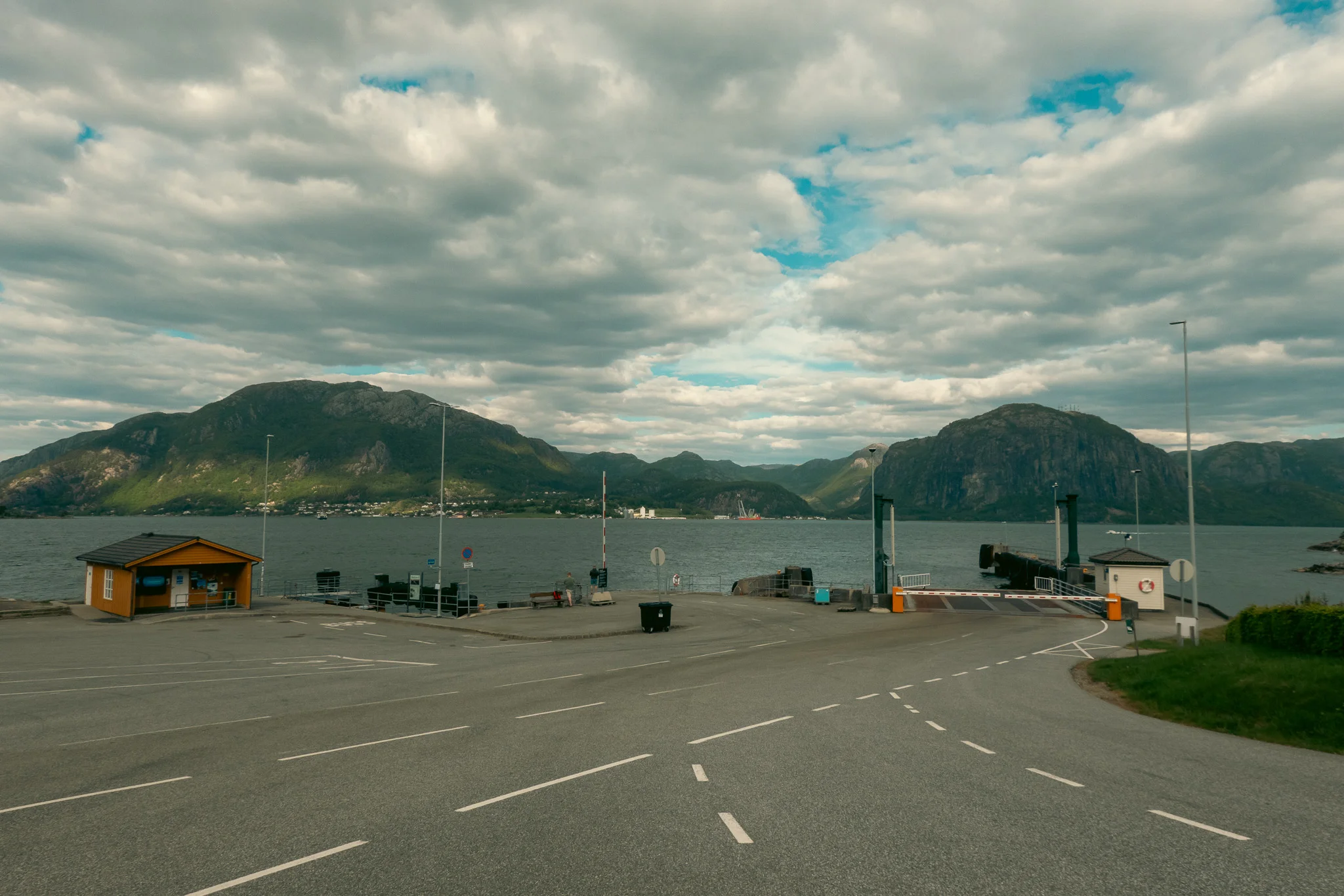 A ferry dock with water and mountains in the background on a cloudy day.