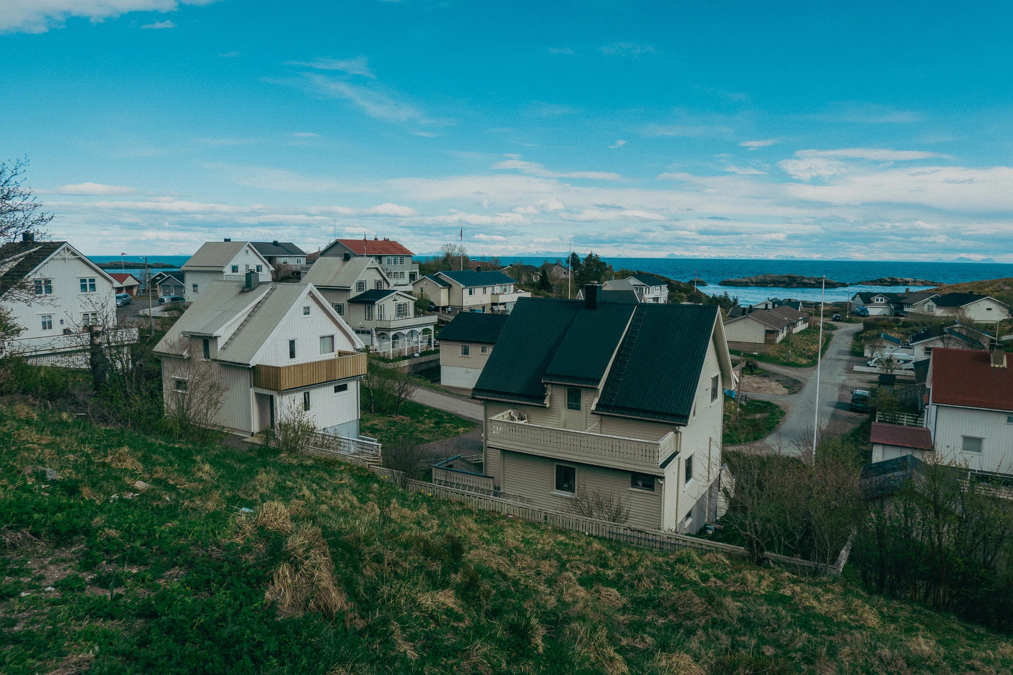 Small cottages in a fishing village on the water with green grass in the foreground
