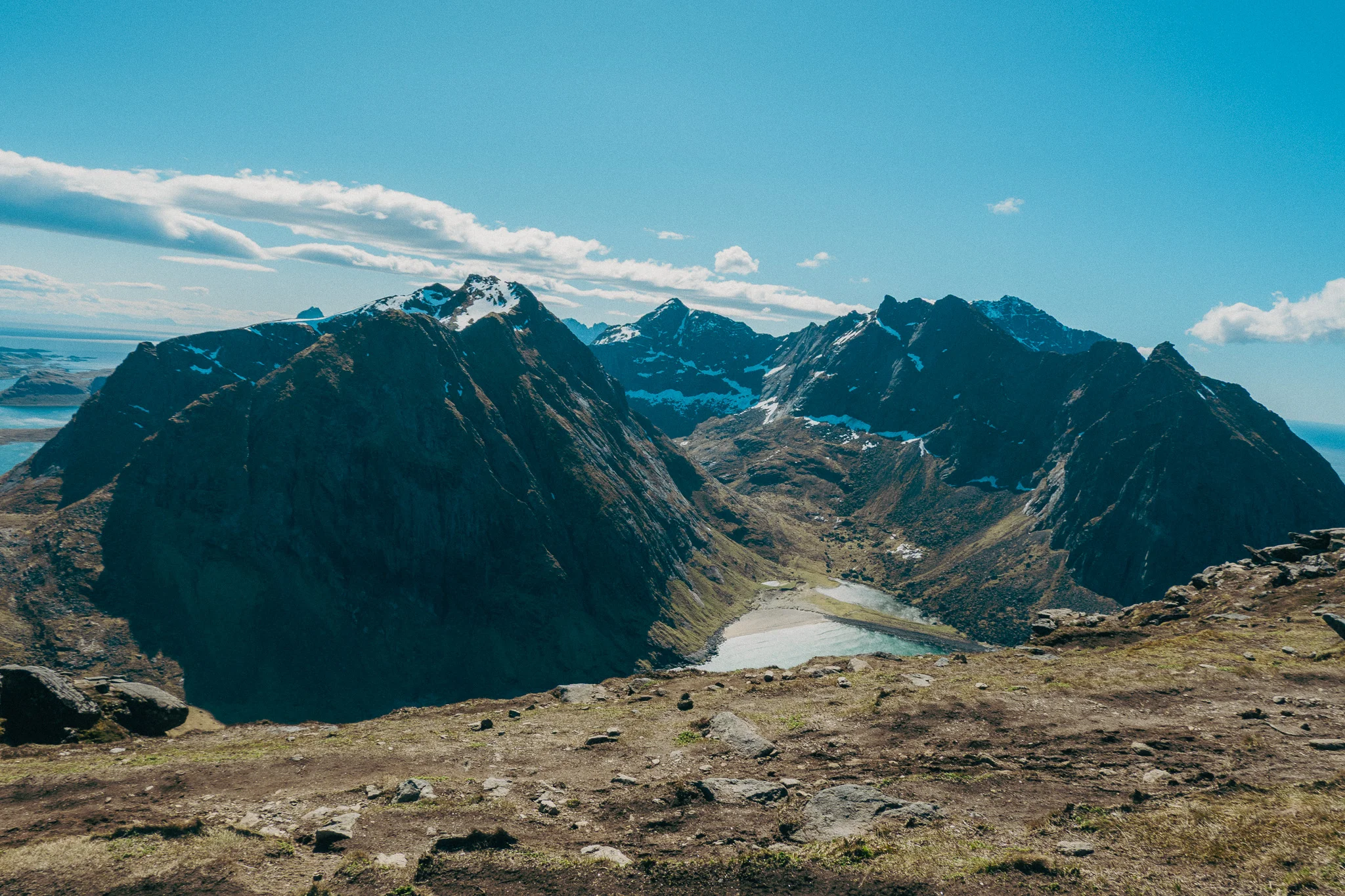 Snow capped mountains and blue sky with water in the foreground