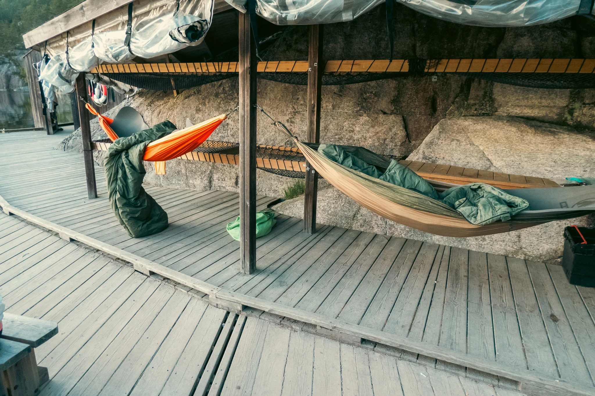 Two hammocks hanging underneath a shelter on a dock.