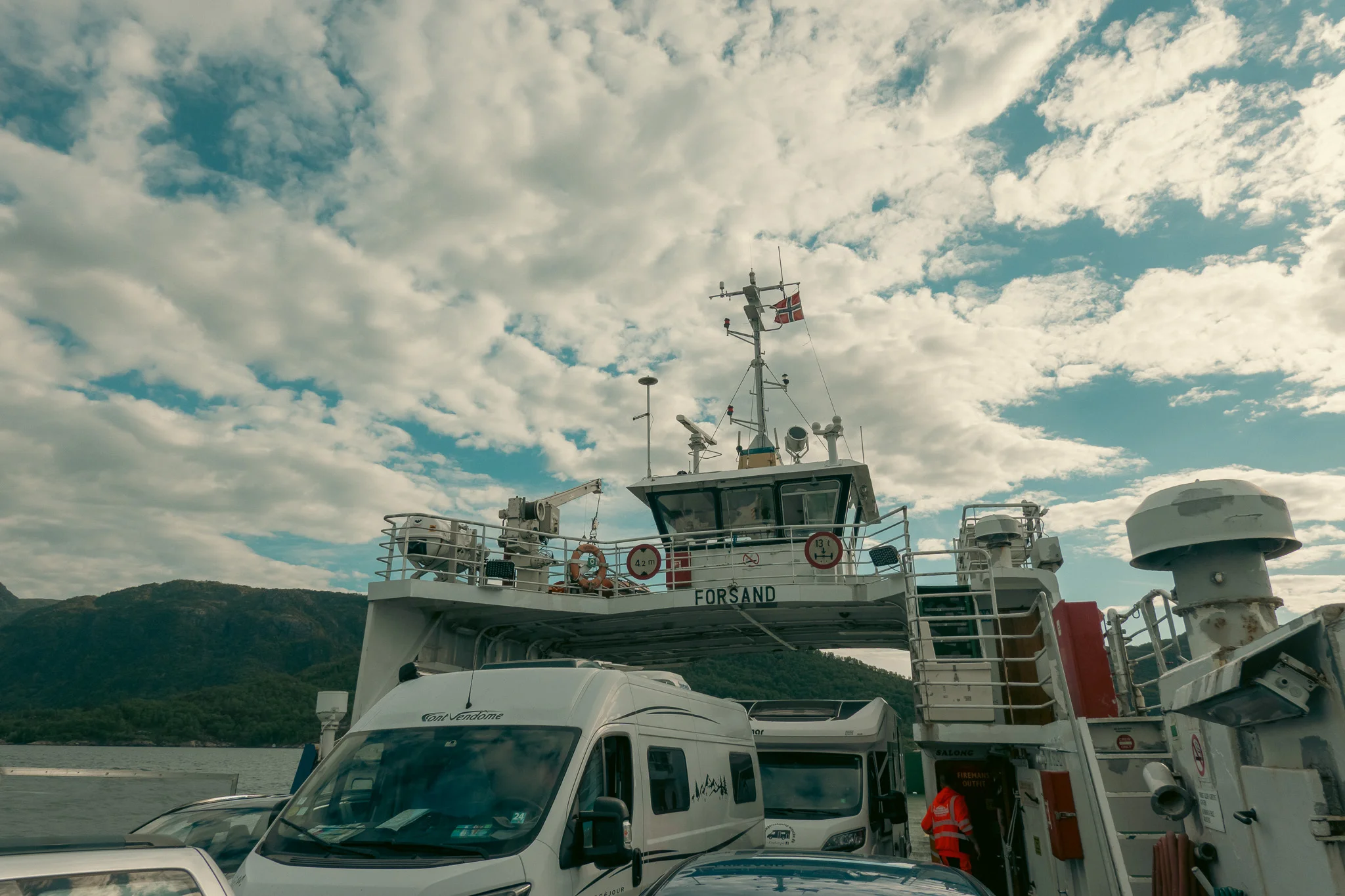 A ferry captain's tower with cars on the boat on a cloudy day.