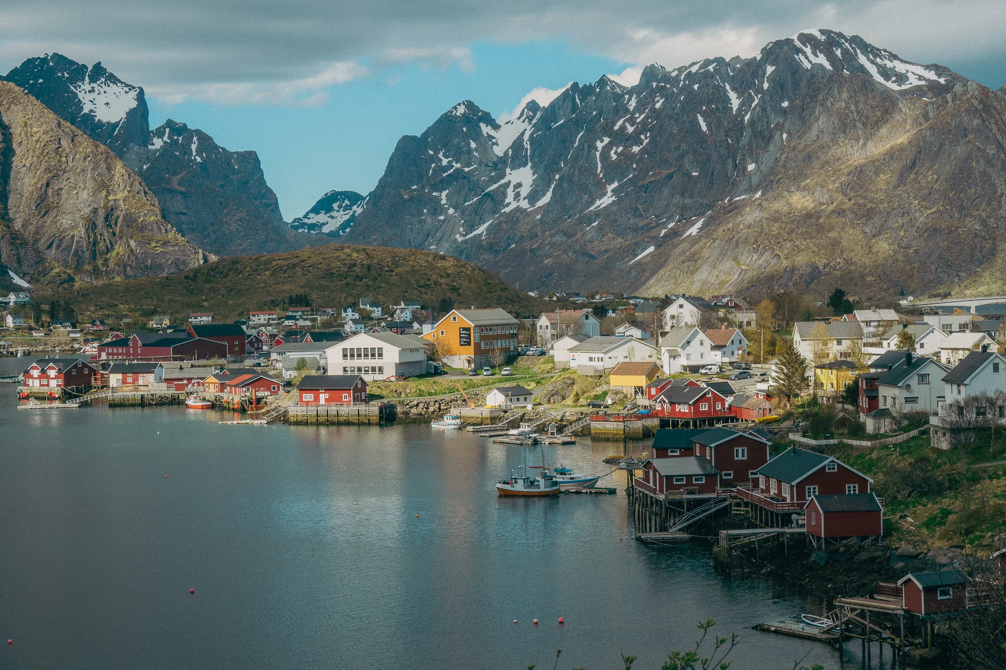 Expansive snow-capped mountains surround a small fishing village on the water