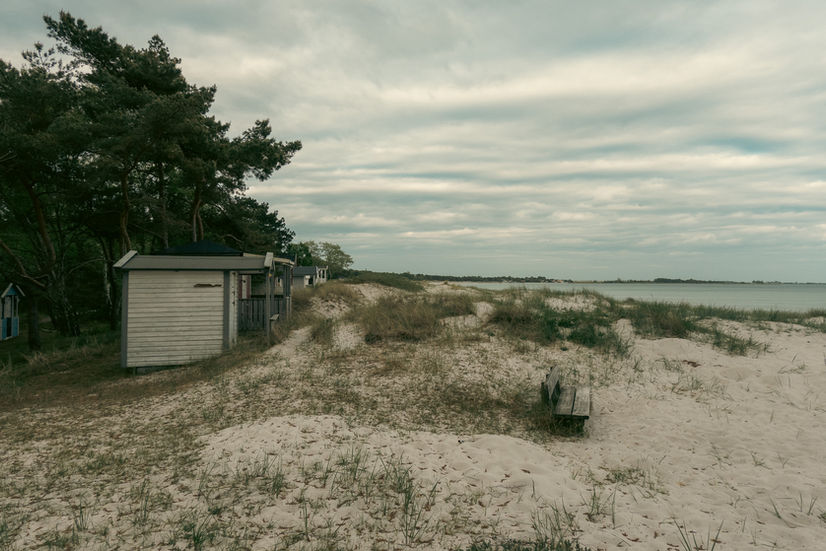 A wide angle view of the beach cottages, sand dunes, and beach grass at Höllviken beach in Sweden