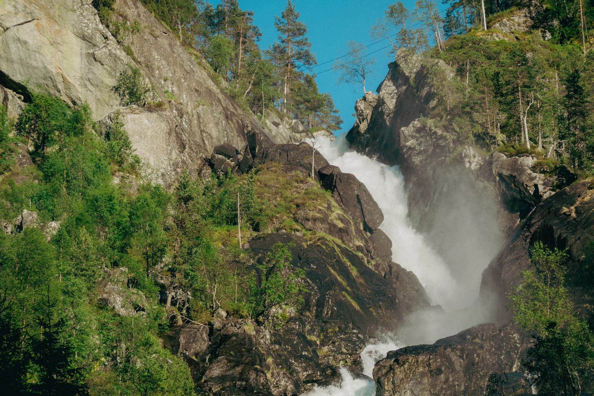 Waterfall cascading between rocks with trees and mountains in the background