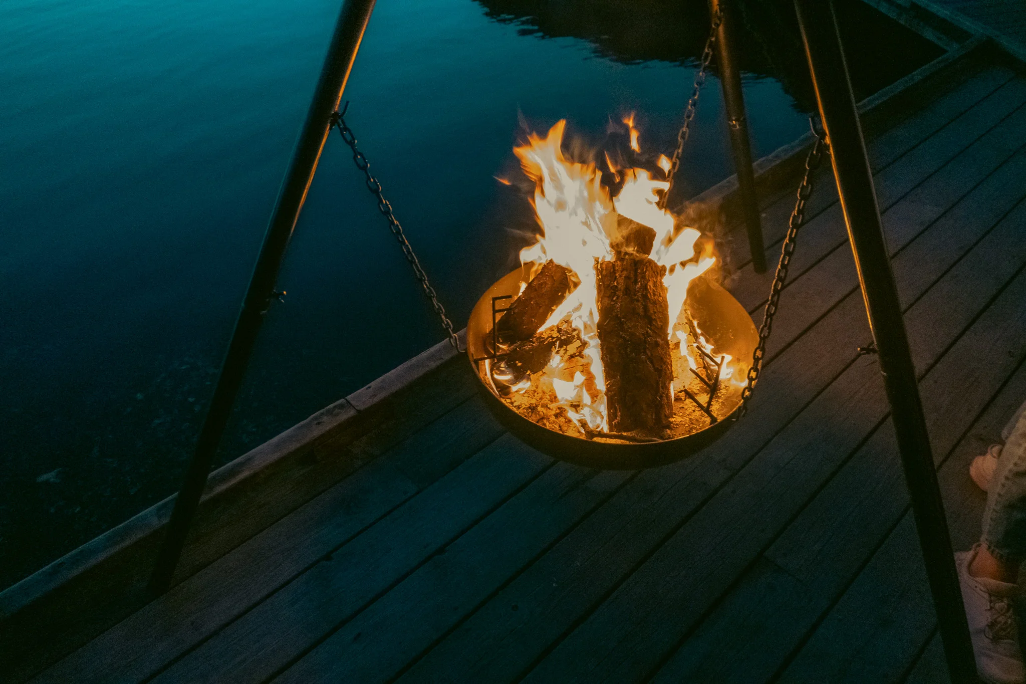 A campfire burning on a dock along side a lake at night in Norway