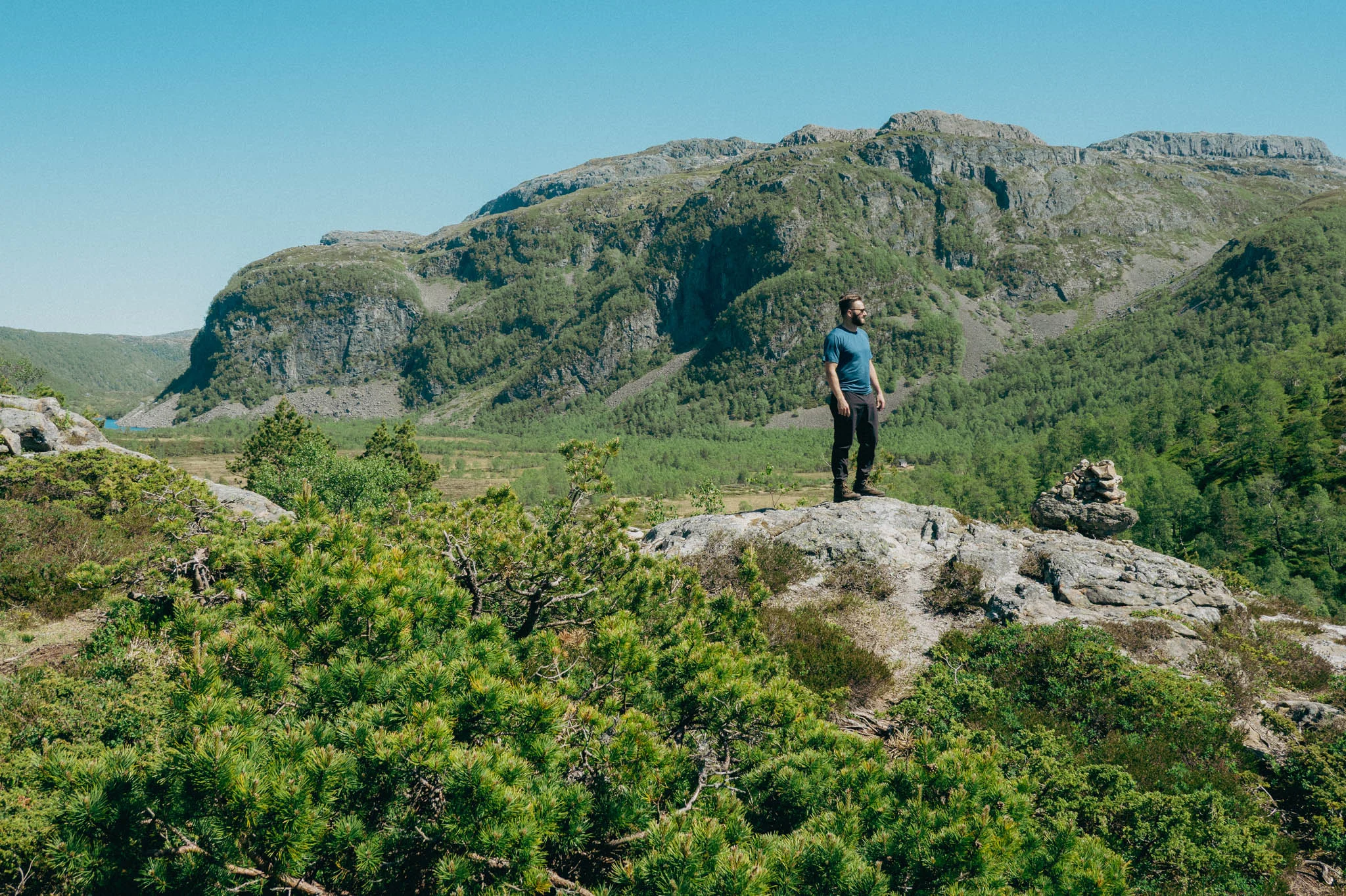 Man standing on a rock looking into the distance with mountains in the background in Norway