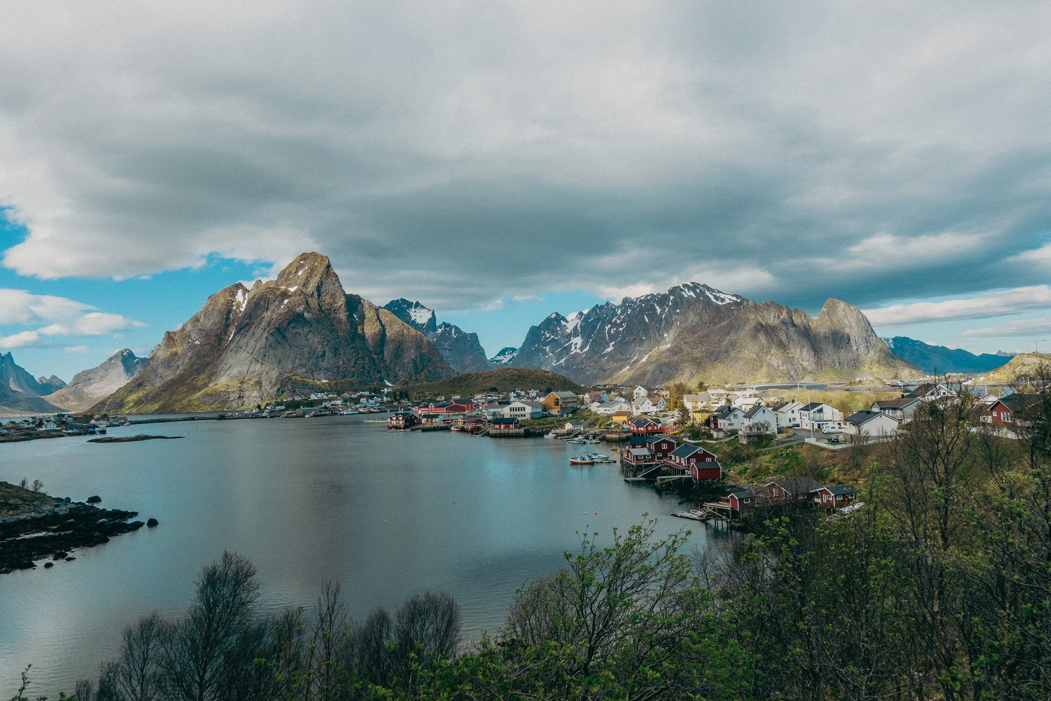Expansive snow-capped mountains surround a small fishing village on the water