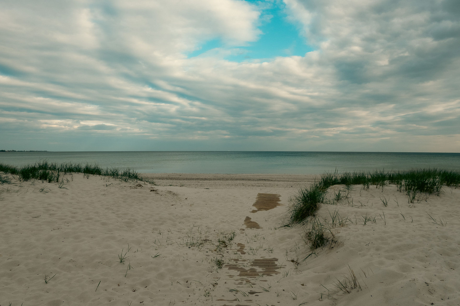 wide shot view of the ocean and swirling clouds in the sky at Höllviken beach in Sweden