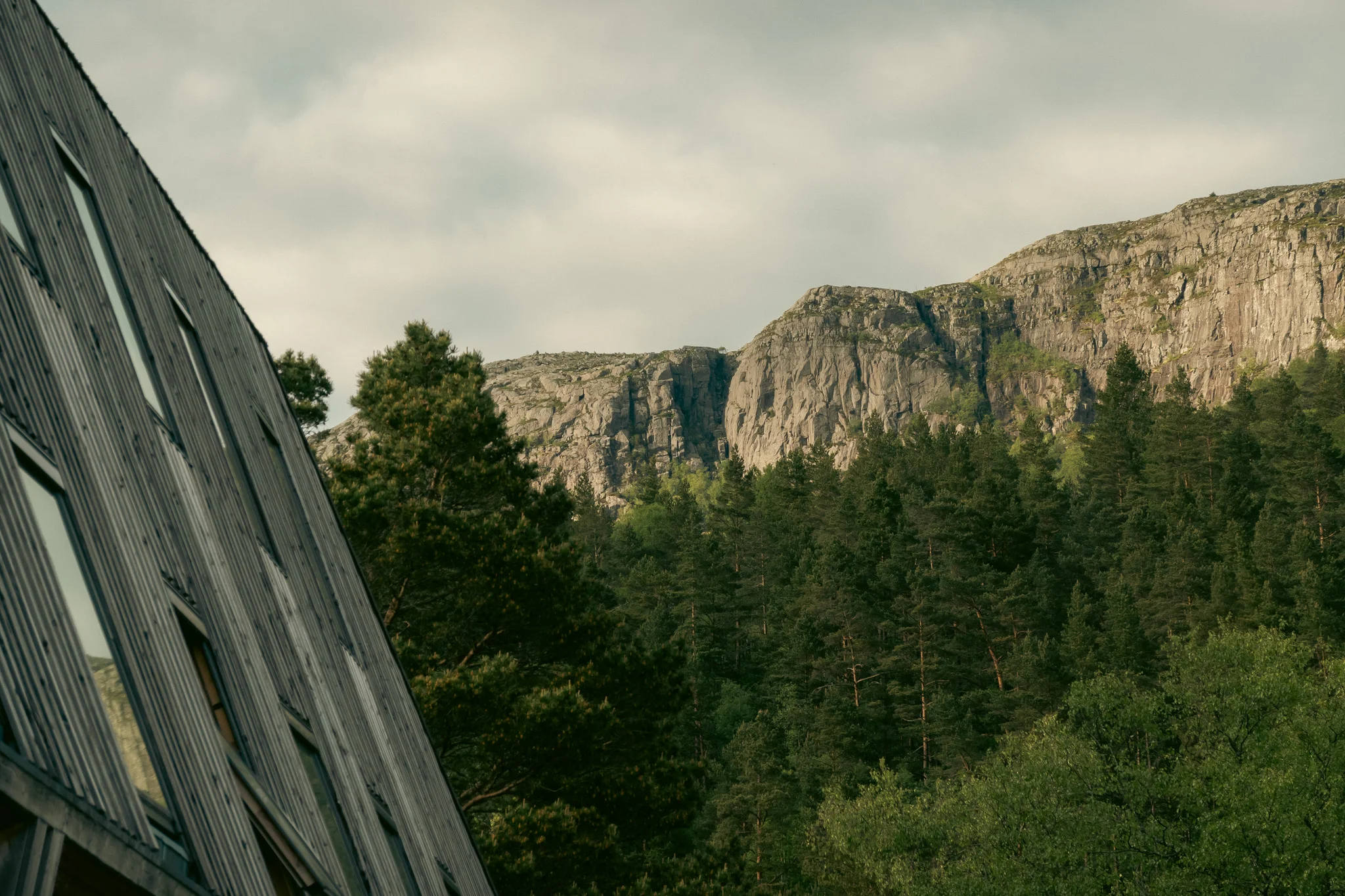 A basecamp building with windows  in front of mountains and trees in the background.