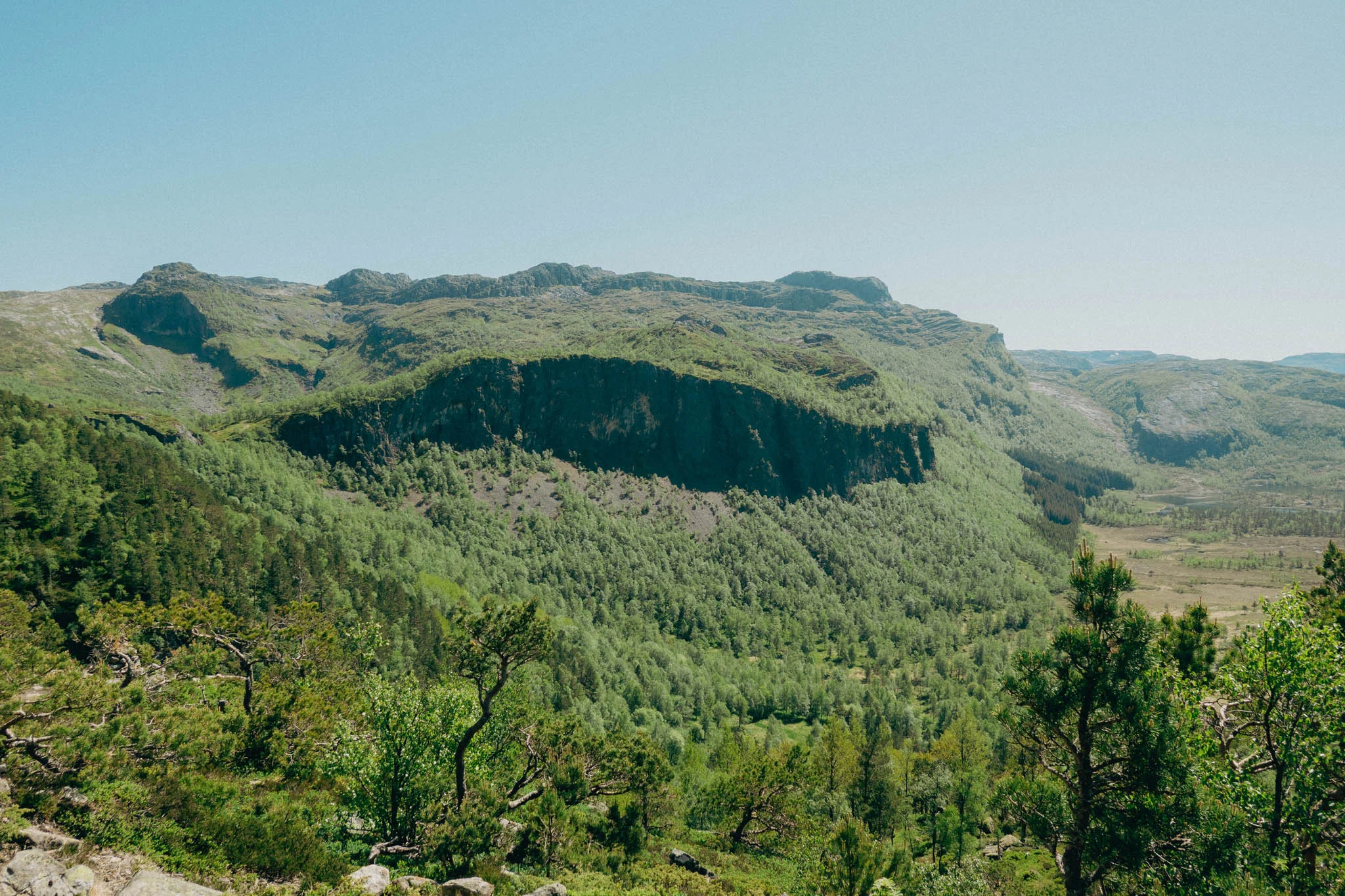 Green trees and mountains surrounding Ritland Crater in Norway