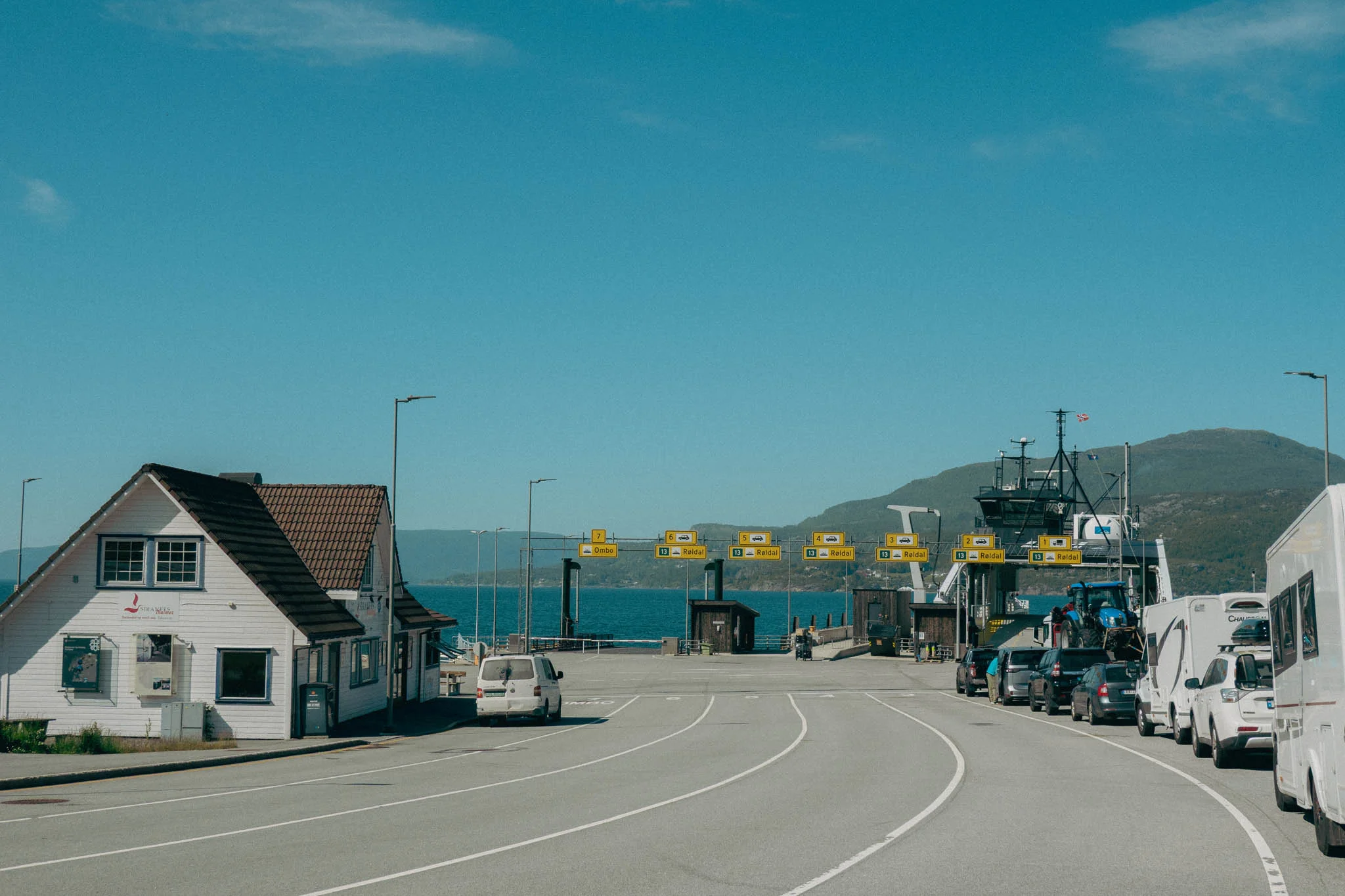 Ferry port with cars lined up waiting to board the ferry with blue water in the background