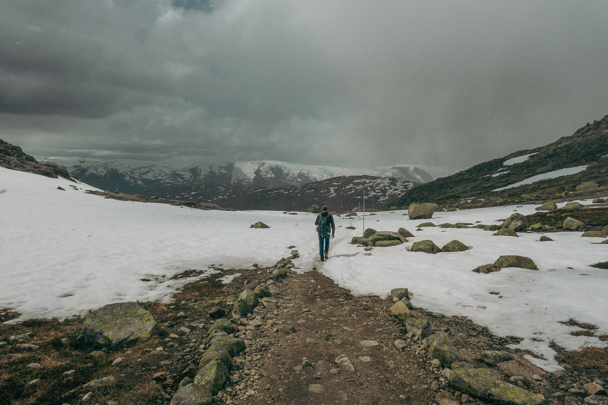 Dark cloudy skies and hailstorm forming with snow and rocks surrounding the Trolltunga trail in Norway