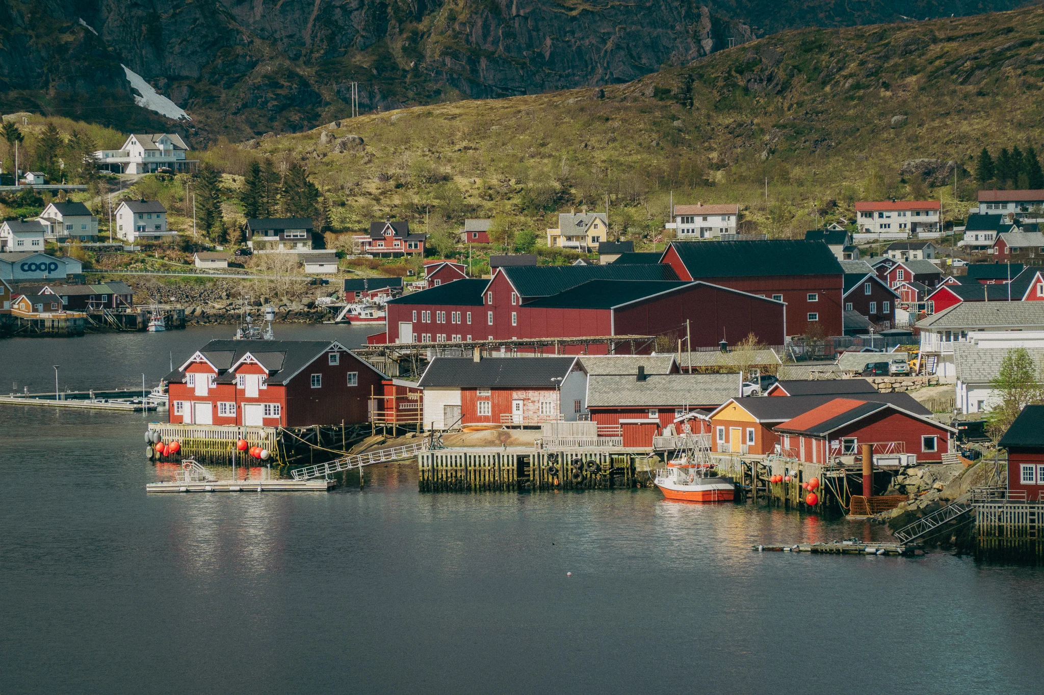 Small red buildings with black roofs in a fishing village on the water