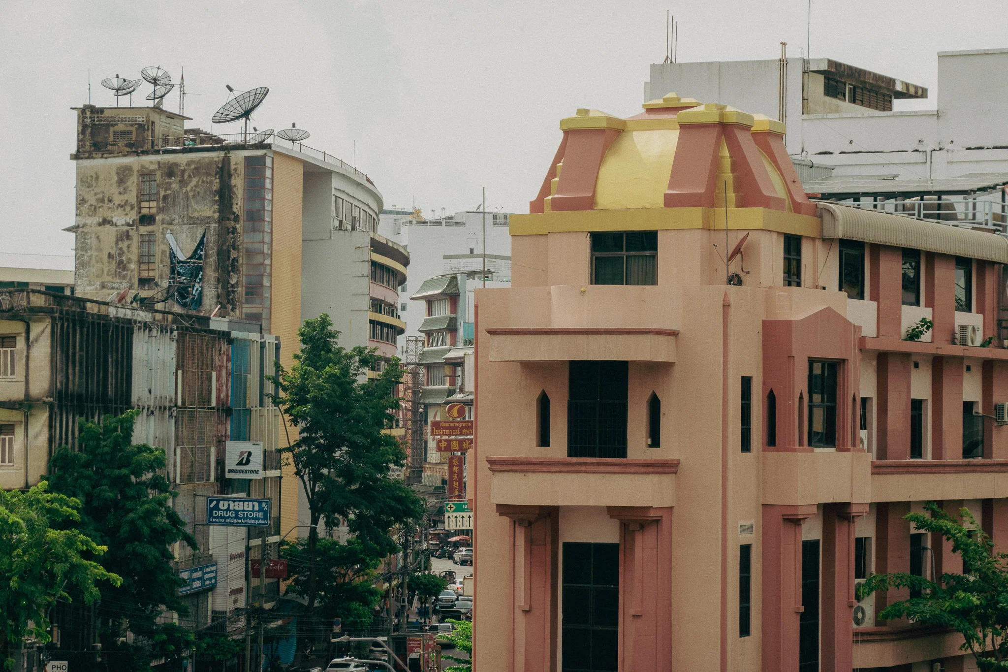 Large pink apartment building surrounded by green trees and white buildings