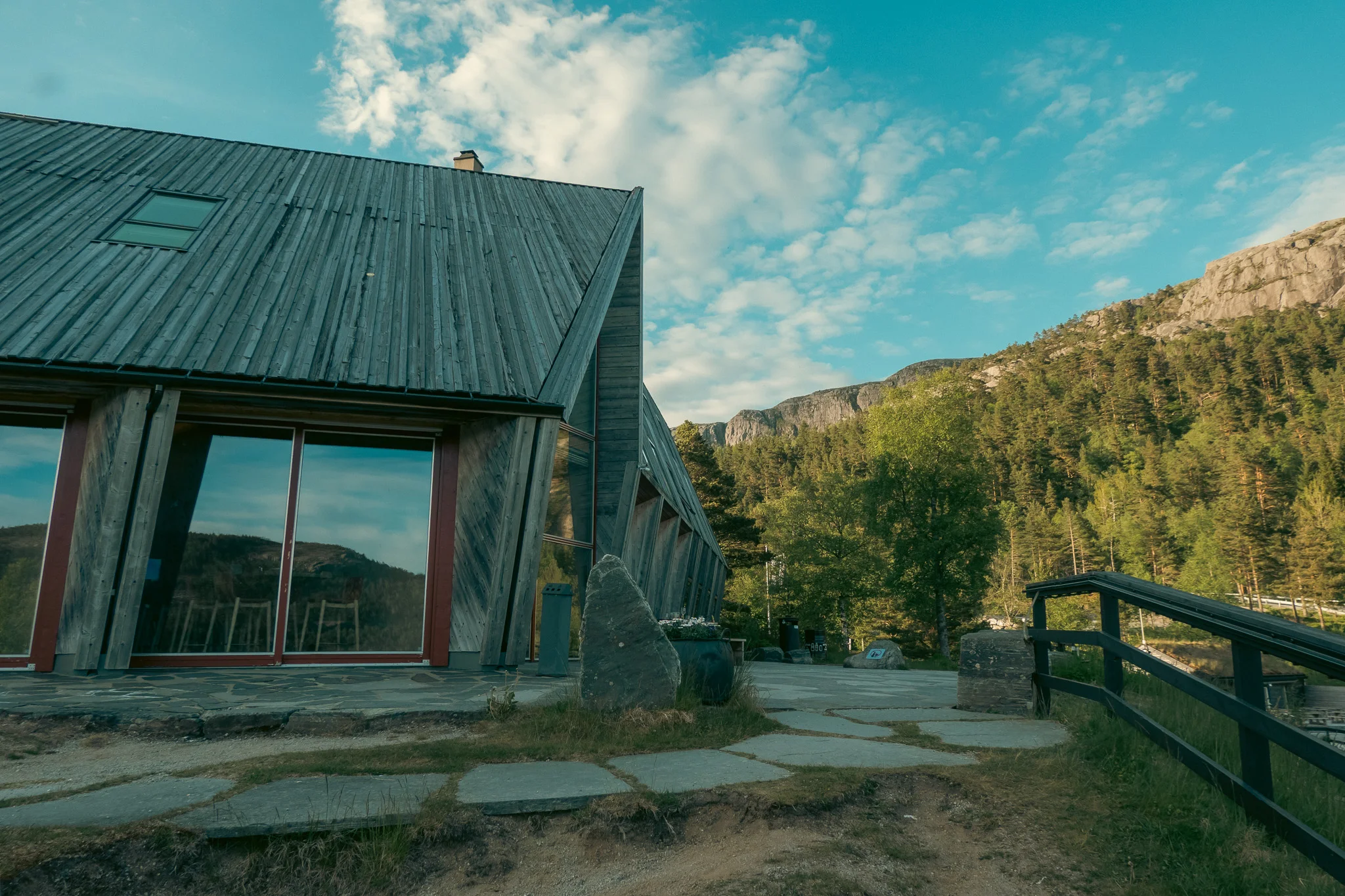 A basecamp building with blue skies and a tree-lined mountain in the background at sunset.