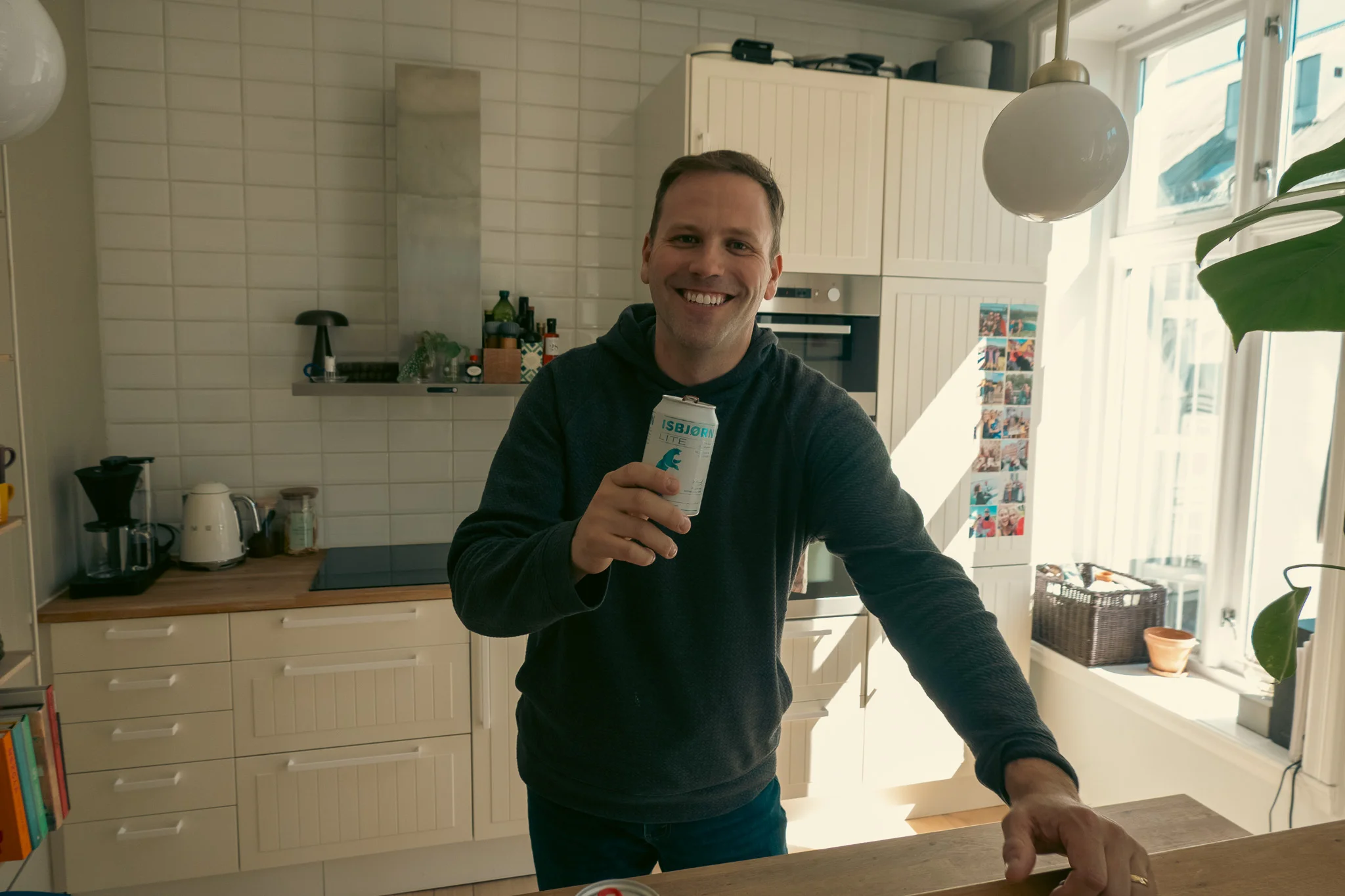 Hunter standing at a counter in the kitchen in an apartment in Oslo, Norway toasting with a beer in his hand.