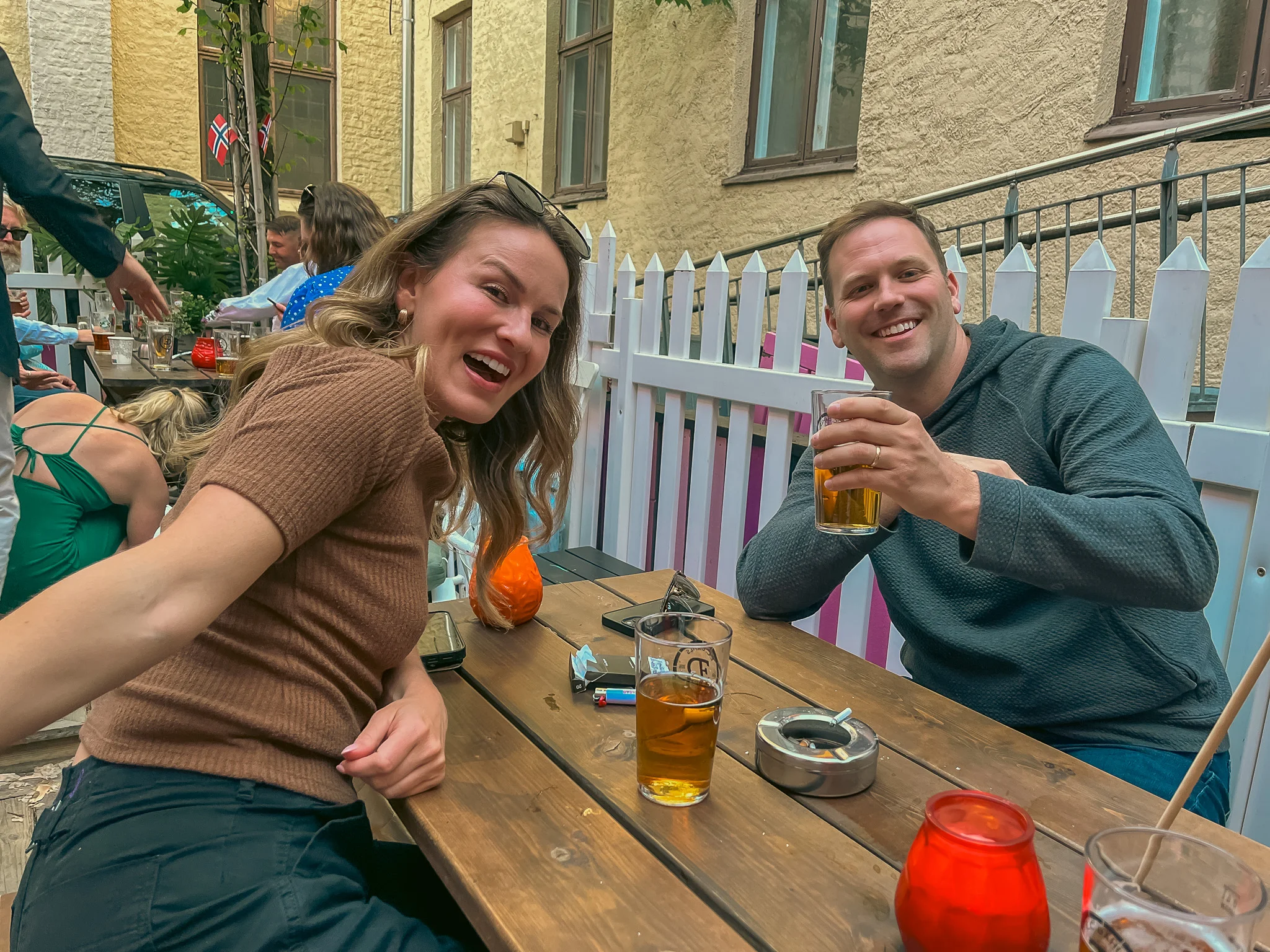 Kelly and Hunter toasting drinks and posing for a picture on the back patio of Rebell bar celebrating Constitution Day in Oslo, Norway