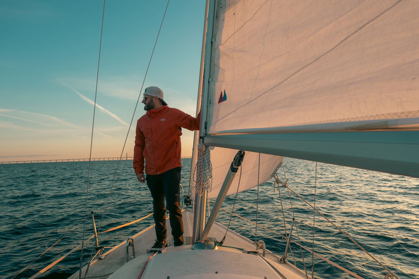 Doug holding on to the mast of a sailboat at sunset in Malmo Sweden