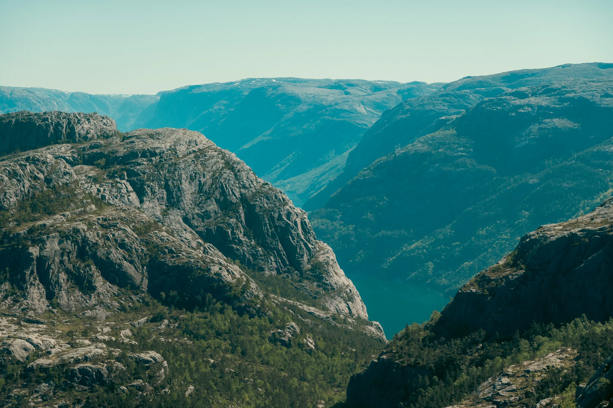 Rocky mountains and a fjord on a clear blue sky day.