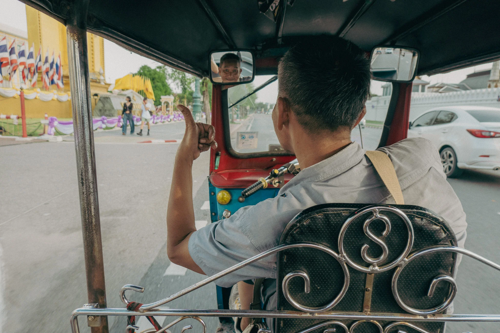 Tuk-tuk driver making a hand gesture while driving