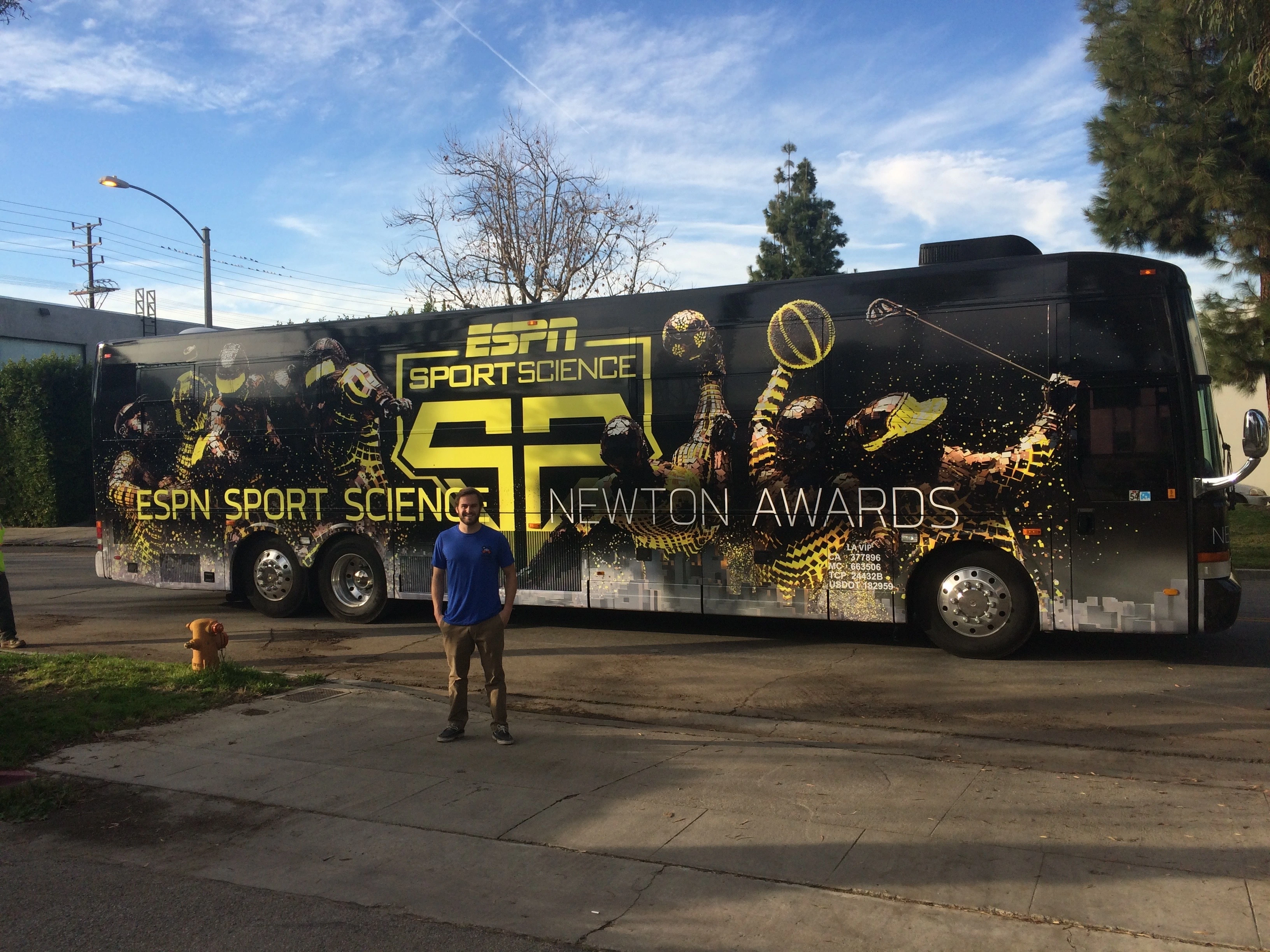 Doug Newton posing in front of the ESPN Sport Science Newton Awards bus wrap that he designed