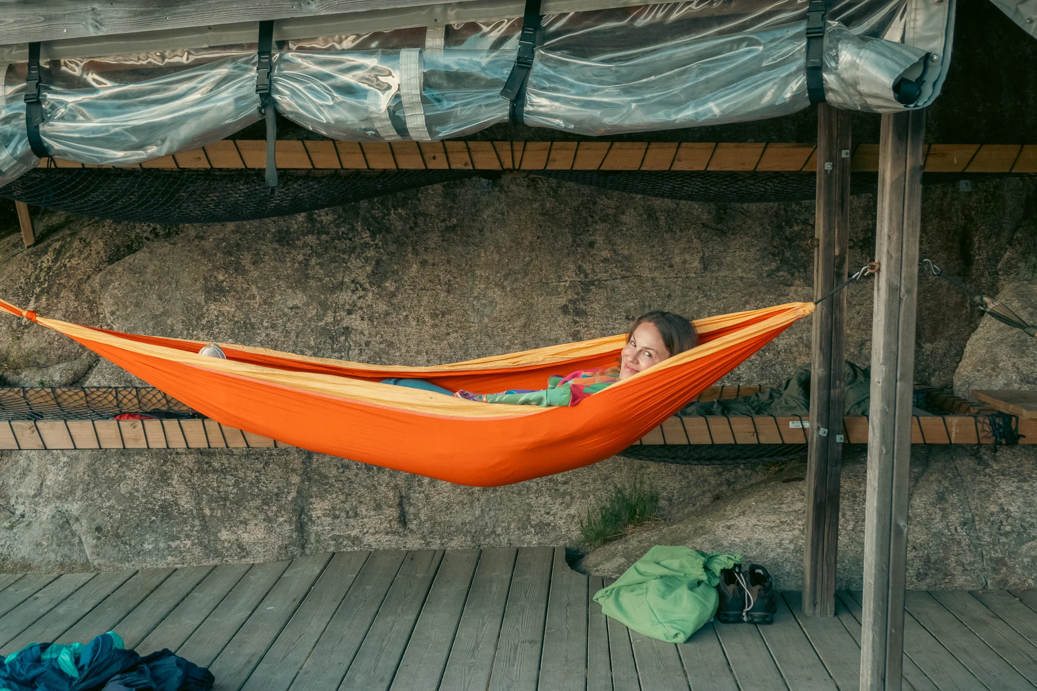 A woman laying in a hammock under a wooden shelter on a dock in Norway.