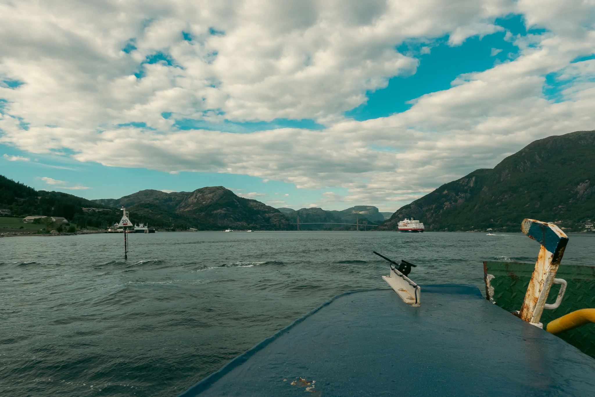 Metal sides of a ferry on a fjord with mountains in the background.