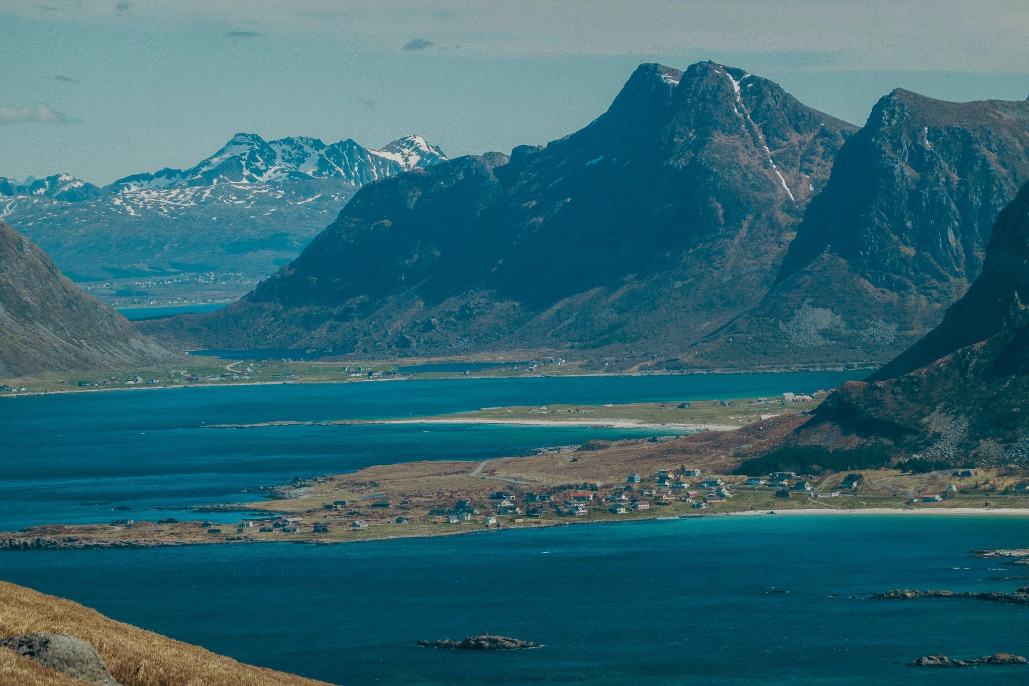 Distant mountains alongside the water with snow-capped mountains and blue sky in the background