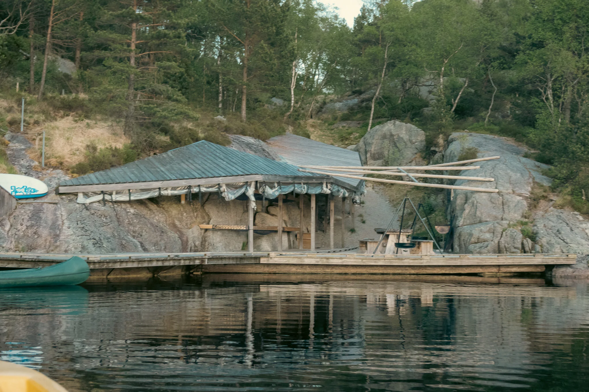 A small dockside campsite with a picnic table and shelter and water in the foreground.
