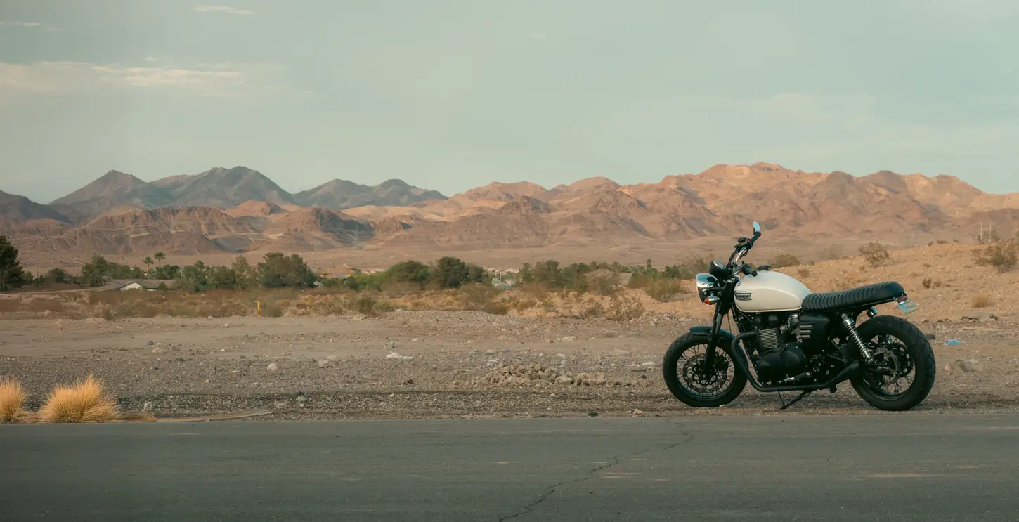 Doug Newton's Triumph Bonneville cafe racer in the desert at sunset with mountains in the background