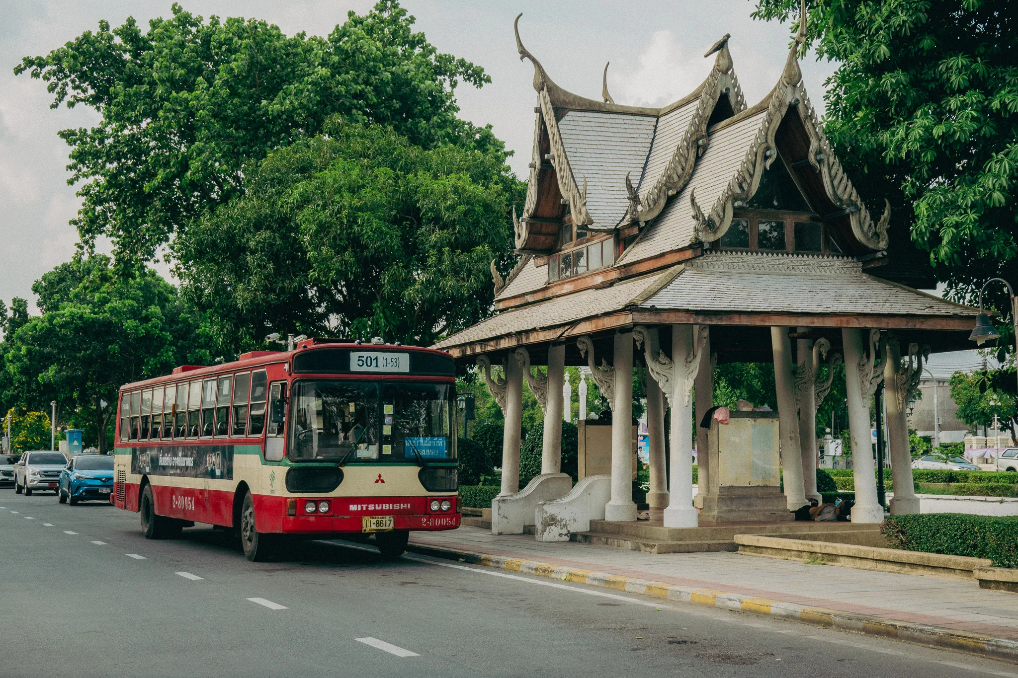 Red and White vintage bus next to a white bus stop struture