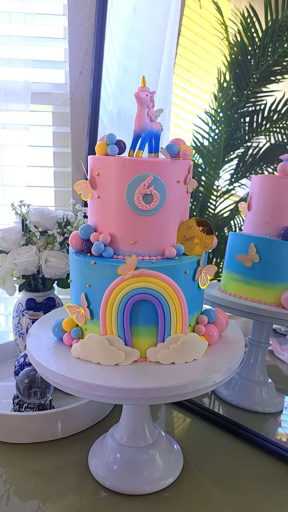 Two-tier birthday cake with rainbow, butterflies, and number 6