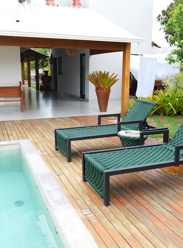 Poolterrasse mit Sonnenliegen und Tisch auf Holzdielen