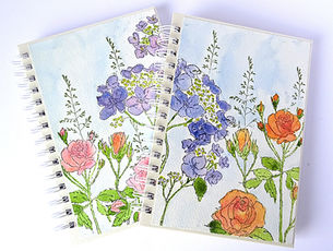 front covers of notebooks featuring watercoloured hydrangeas in purple and roses in orange and pink