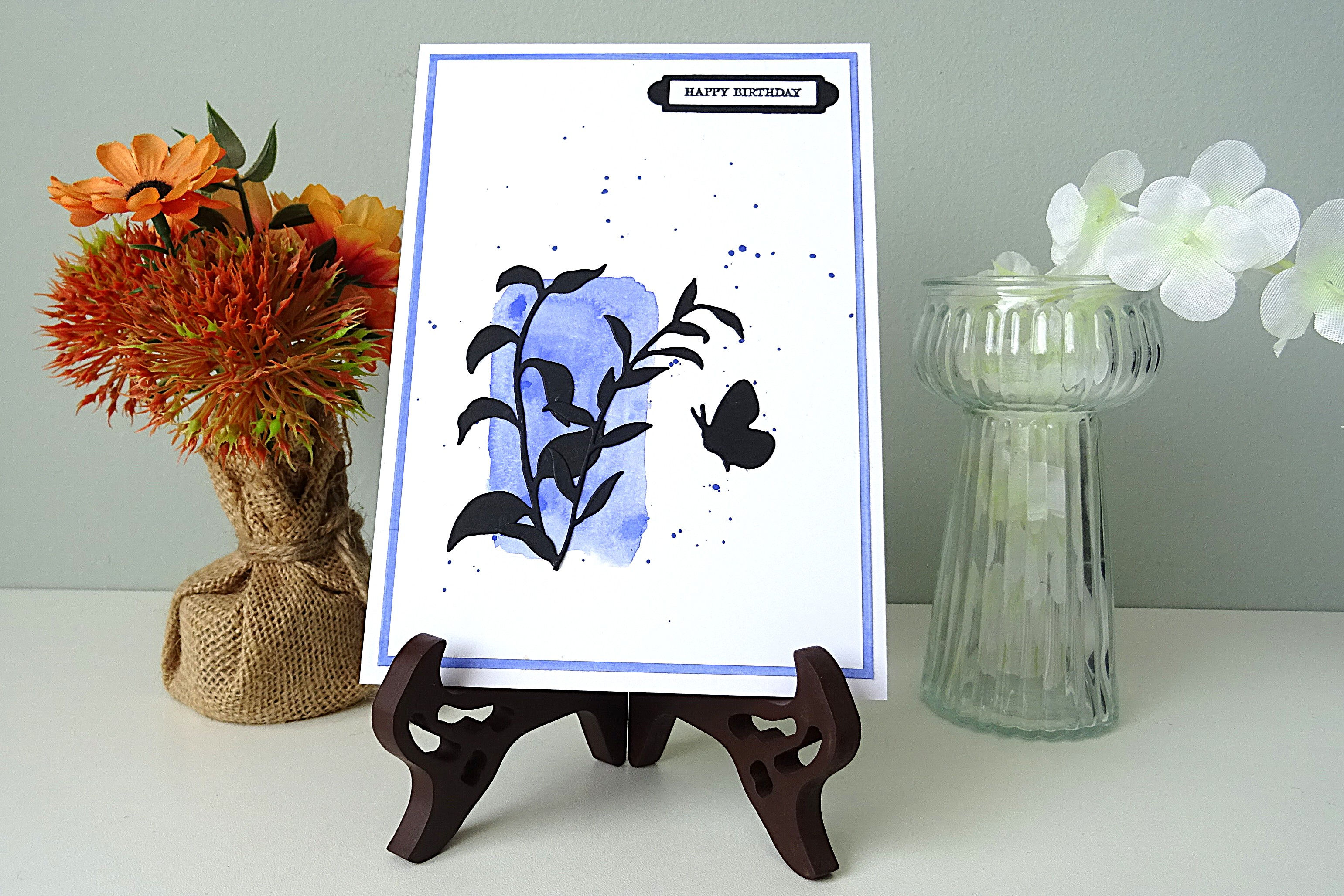 purple colour block in left hand corner; green leaves over top of block; butterfly; Happy Birthday message top right