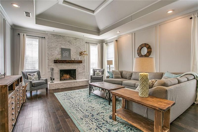 Light gray living room with gray couch, blue and green accents, and a limewashed white fireplace