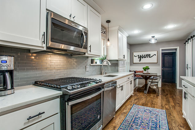 White kitchen cabinets, black hardware, gray backsplash, and built-in kitchen nook
