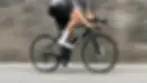 A cyclist riding a BMC road bike in front of a blurred wall