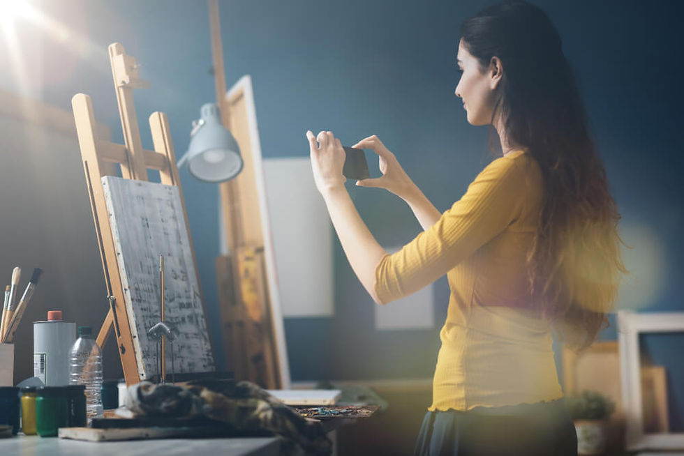 An artist taking a photograph of a painting on an easel
