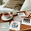 Thumbnail: Cozy wooden tray on a bed with a cup of tea, candle, small jewelry dish, and several laid out affirmation cards featuring ill