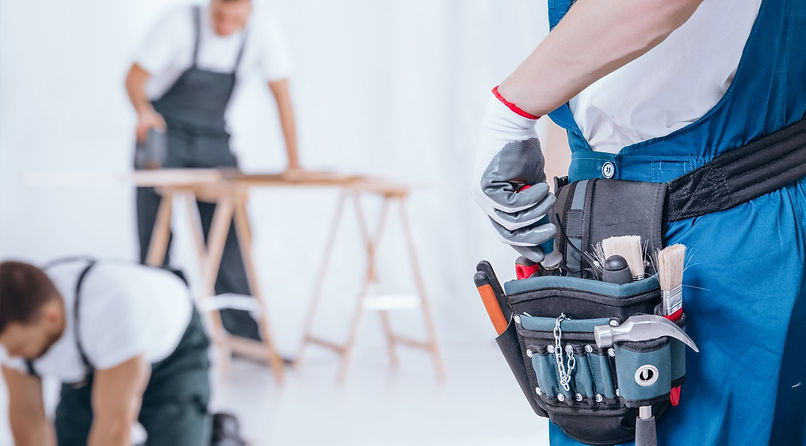 Close-up of handyman wearing gloves and tool belt on blue trousers during home renovation_