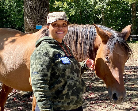 Group participant smiling at camera while touching horse
