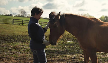Amanda standing with a horse in a field